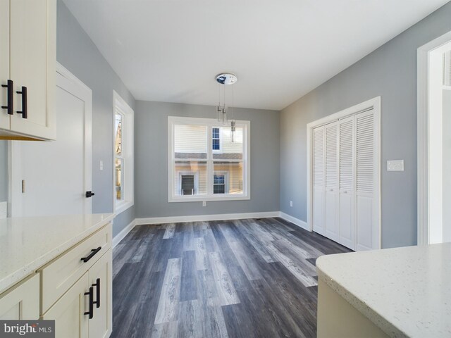 unfurnished dining area with baseboards and dark wood-type flooring