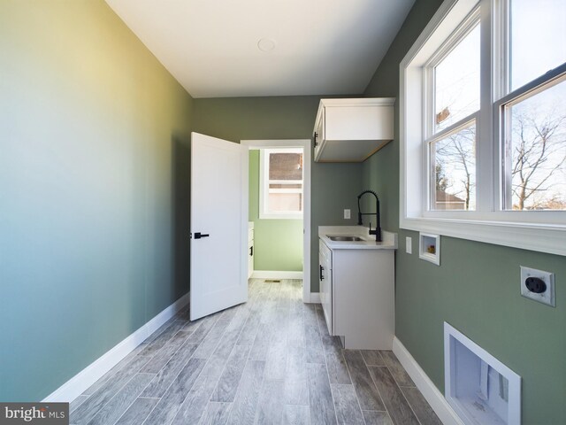 laundry room with a sink, visible vents, light wood-type flooring, cabinet space, and electric dryer hookup