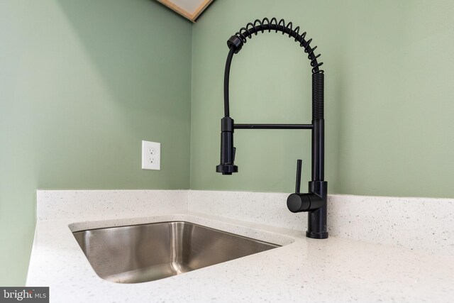 interior details featuring light stone counters and a sink