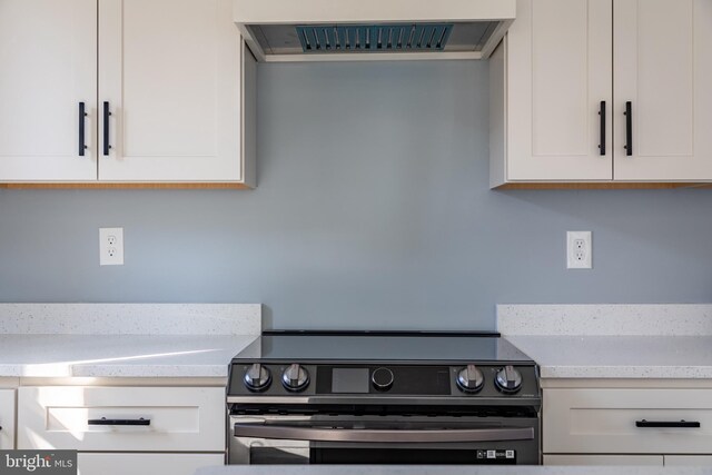 kitchen with range hood, white cabinetry, and electric range