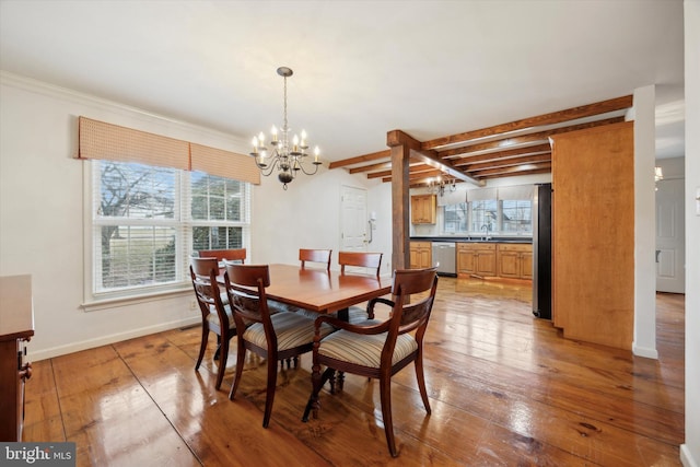 dining area featuring a notable chandelier, beam ceiling, wood-type flooring, and sink