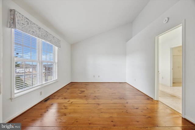 spare room featuring lofted ceiling and light hardwood / wood-style flooring