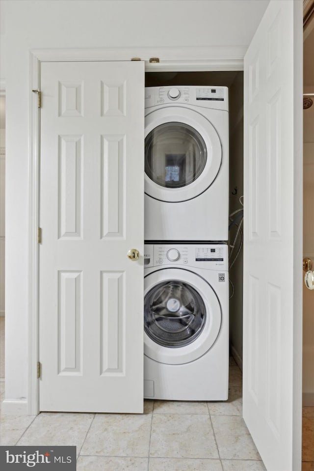 washroom featuring stacked washer / dryer and light tile patterned floors