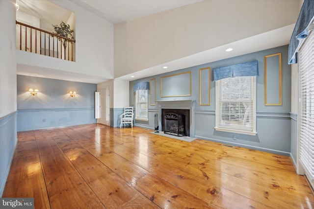 unfurnished living room featuring hardwood / wood-style floors, a healthy amount of sunlight, and a high ceiling