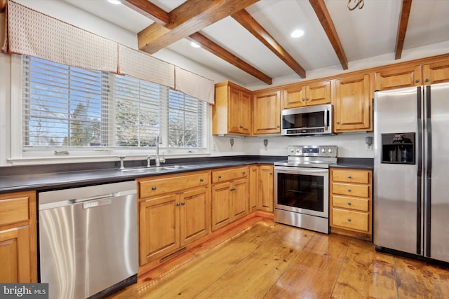 kitchen featuring sink, stainless steel appliances, beamed ceiling, and light wood-type flooring