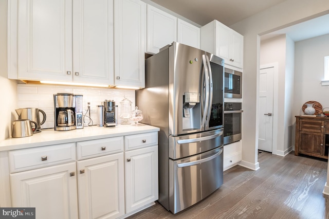 kitchen with dark wood-type flooring, tasteful backsplash, stainless steel appliances, and white cabinets