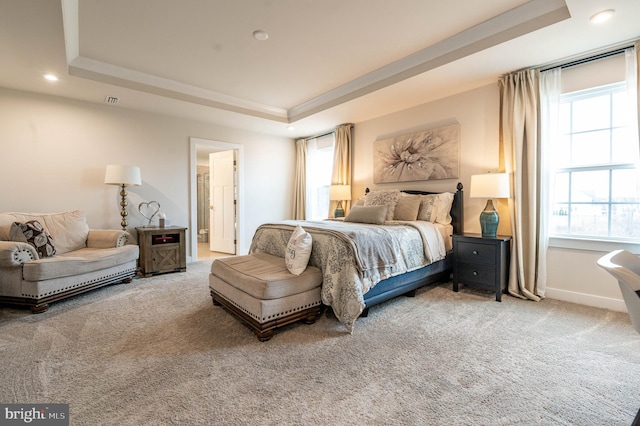 bedroom with a tray ceiling, multiple windows, and carpet floors