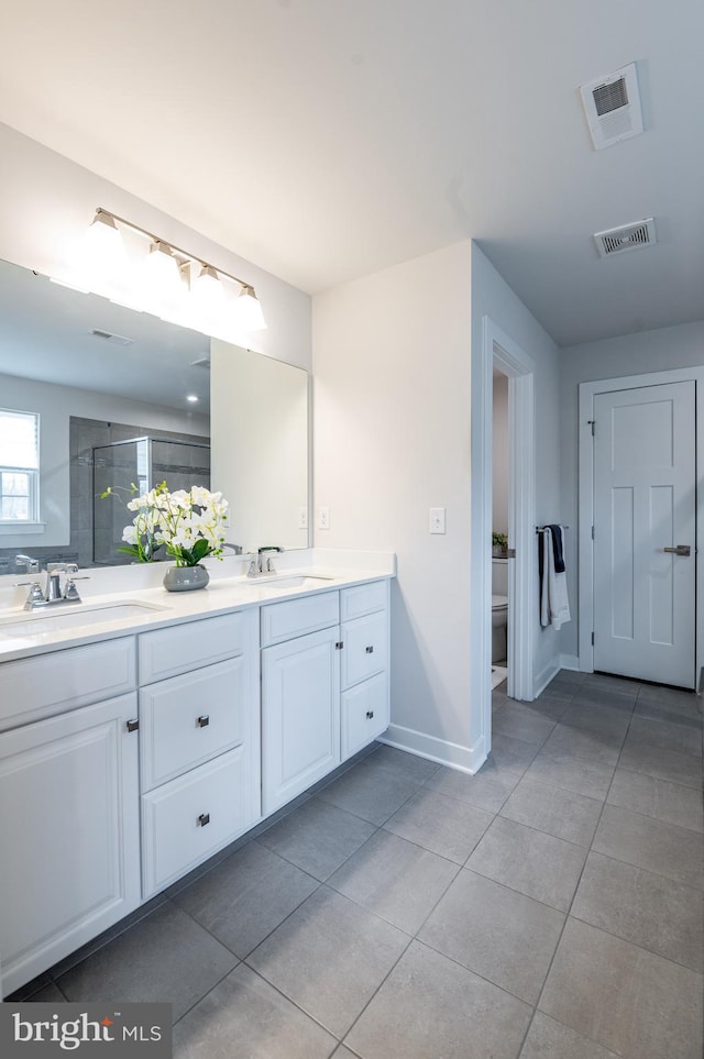 bathroom with tile patterned floors, toilet, vanity, and a shower with door