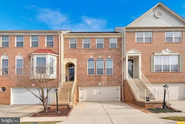 multi unit property featuring a garage, brick siding, and driveway