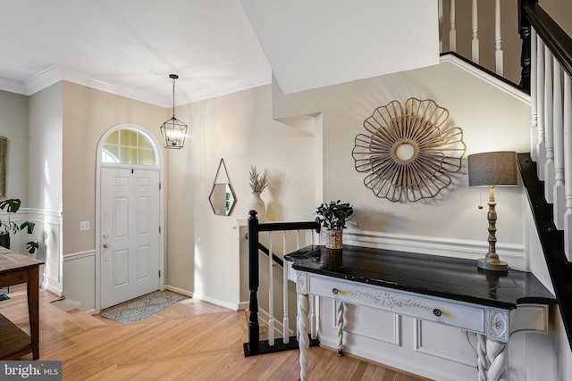 entryway with ornamental molding, baseboards, light wood finished floors, and an inviting chandelier