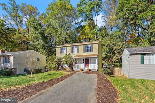 view of front facade featuring covered porch, fence, and a front lawn