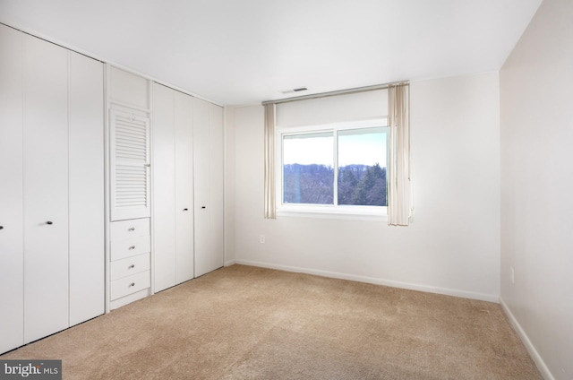 unfurnished bedroom featuring light carpet, a closet, visible vents, and baseboards