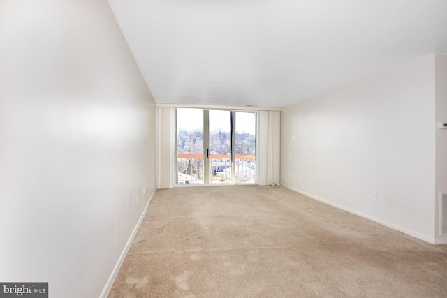 unfurnished room with light carpet, visible vents, floor to ceiling windows, and baseboards