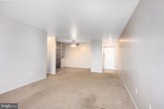 empty room featuring light colored carpet, ceiling fan, and baseboards