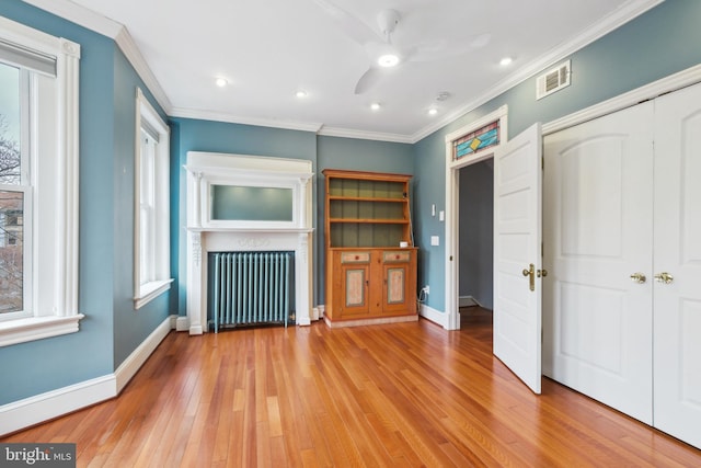 unfurnished living room featuring radiator heating unit, light wood-type flooring, ceiling fan, and ornamental molding