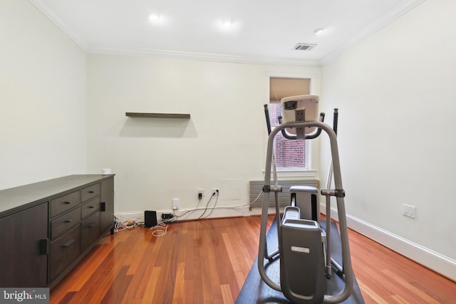 exercise area featuring wood-type flooring and ornamental molding