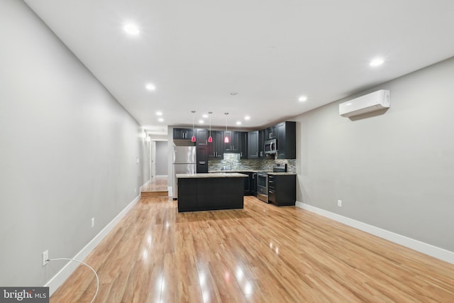 kitchen featuring appliances with stainless steel finishes, pendant lighting, a kitchen island, a wall mounted air conditioner, and tasteful backsplash