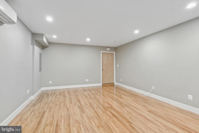 unfurnished room with light wood-type flooring and a wall unit AC