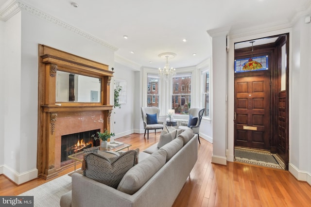 living room featuring ornamental molding, hardwood / wood-style floors, a notable chandelier, and a premium fireplace