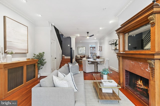 living room with dark hardwood / wood-style flooring, ceiling fan, crown molding, and a high end fireplace