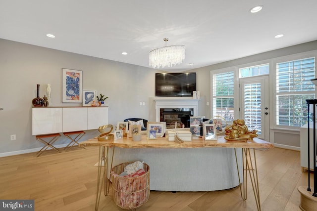 living room featuring light hardwood / wood-style flooring, an inviting chandelier, and a high end fireplace