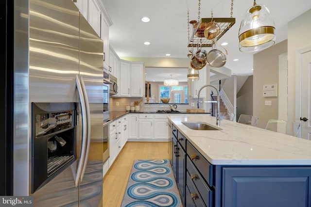 kitchen with white cabinetry, light stone countertops, stainless steel fridge, light hardwood / wood-style floors, and sink