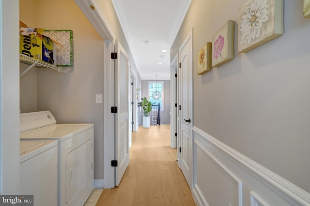 laundry room with ornamental molding, washer and clothes dryer, and light hardwood / wood-style flooring