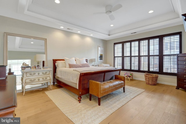 bedroom featuring light hardwood / wood-style flooring, crown molding, and a raised ceiling