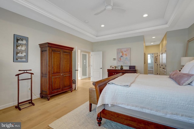 bedroom featuring ensuite bathroom, light hardwood / wood-style floors, ceiling fan, a raised ceiling, and ornamental molding