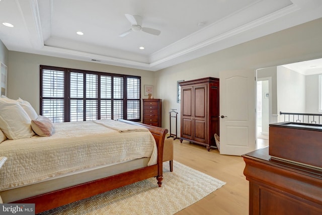 bedroom with light hardwood / wood-style flooring, crown molding, and a raised ceiling