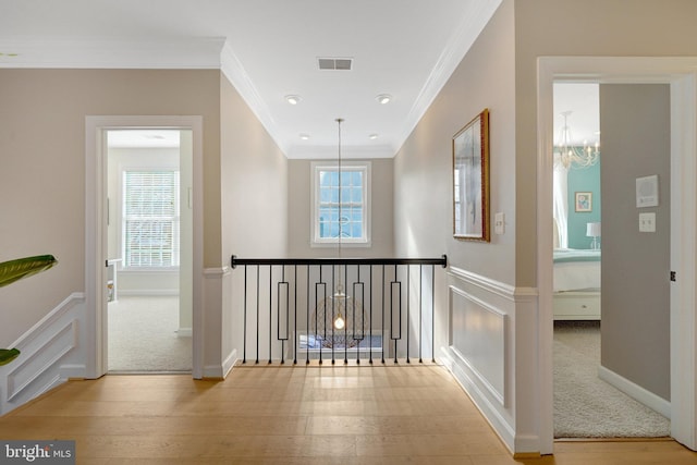 hall with a healthy amount of sunlight, crown molding, and light wood-type flooring