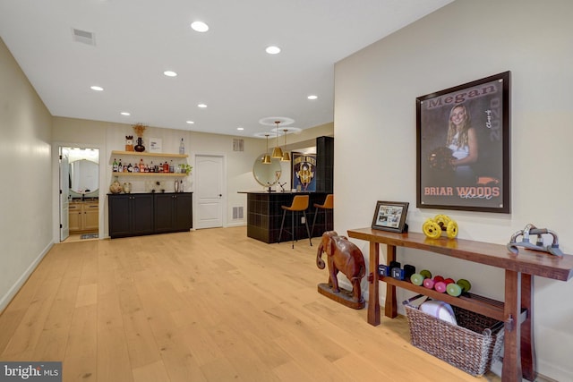 interior space with decorative light fixtures, light hardwood / wood-style floors, and a breakfast bar area