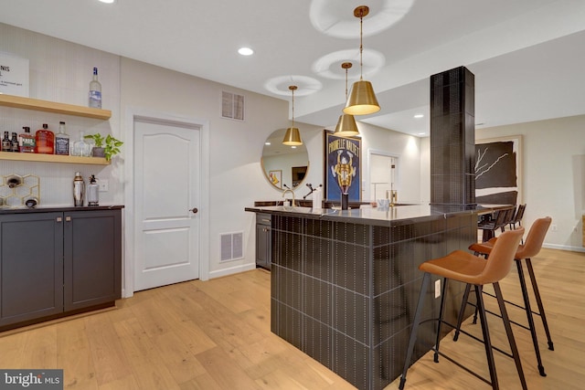 bar with light wood-type flooring and pendant lighting