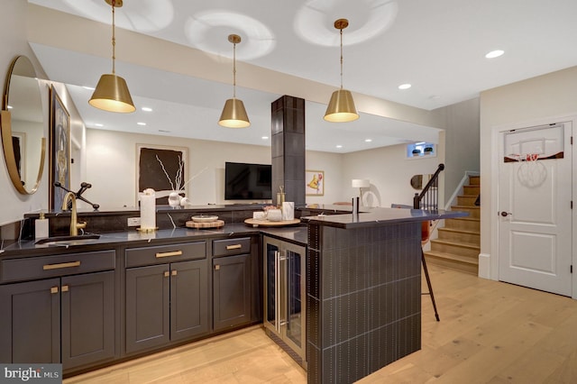 kitchen featuring sink, hanging light fixtures, a kitchen bar, and wine cooler