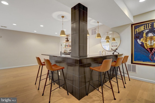 bar with light wood-type flooring and pendant lighting