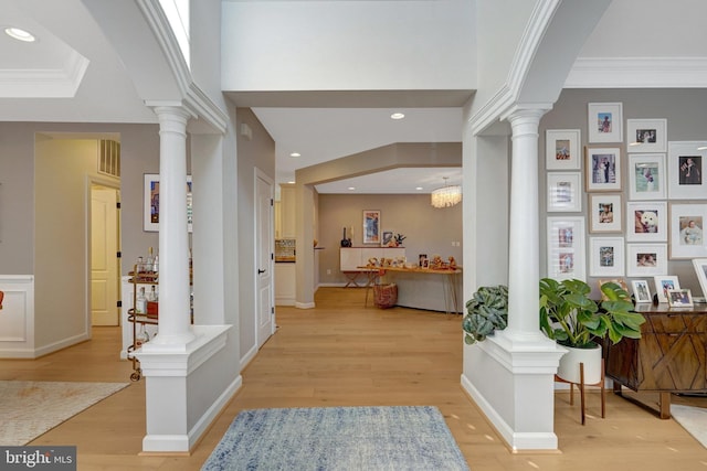 entryway with ornate columns, crown molding, and light hardwood / wood-style floors