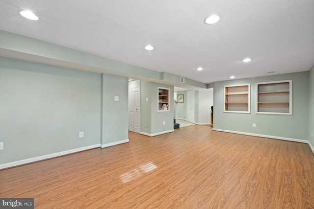 unfurnished living room featuring built in features and light wood-type flooring