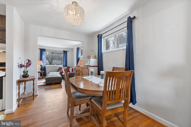 dining room with hardwood / wood-style flooring, a healthy amount of sunlight, and an inviting chandelier