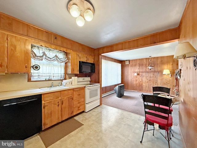 kitchen featuring pendant lighting, sink, wooden walls, and black appliances