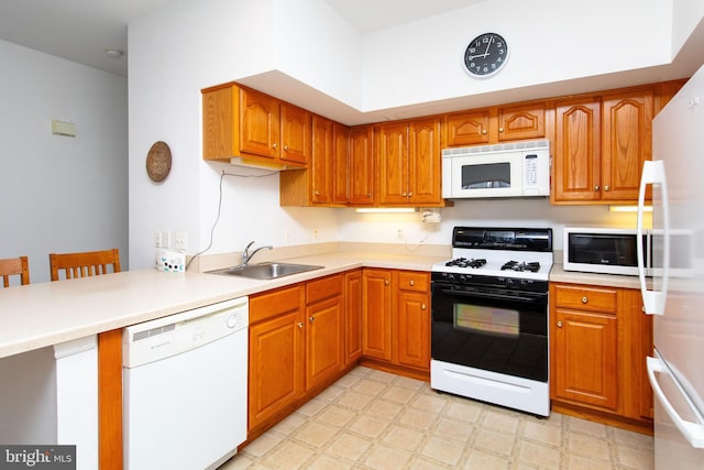 kitchen with white appliances, sink, and a breakfast bar area