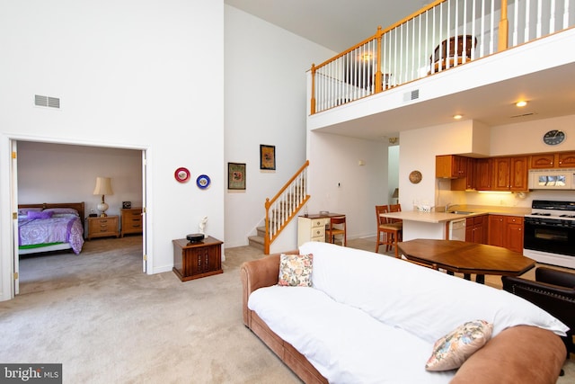 carpeted living room featuring a towering ceiling and sink