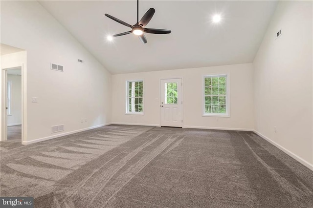 unfurnished living room with dark colored carpet, a healthy amount of sunlight, ceiling fan, and high vaulted ceiling