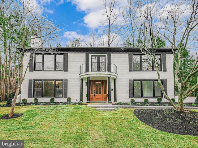 view of front of property featuring a balcony, brick siding, and a front yard