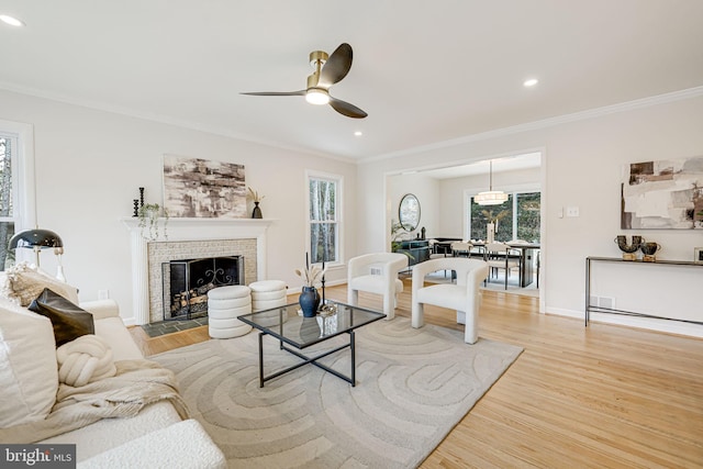 living room featuring light wood-style floors, a brick fireplace, and crown molding