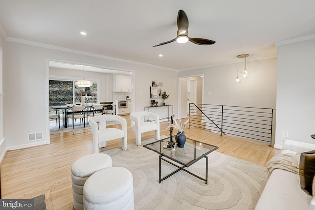 living room featuring light wood finished floors, visible vents, and crown molding