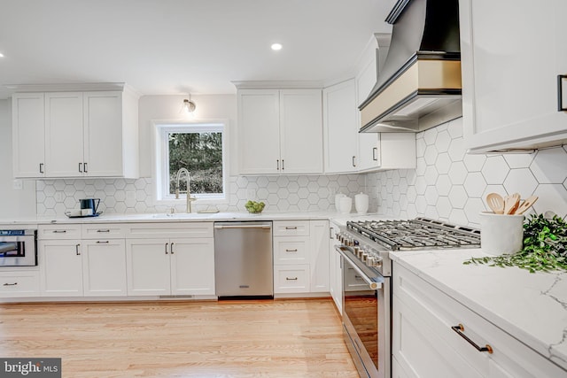 kitchen featuring white cabinets, custom exhaust hood, stainless steel appliances, and a sink