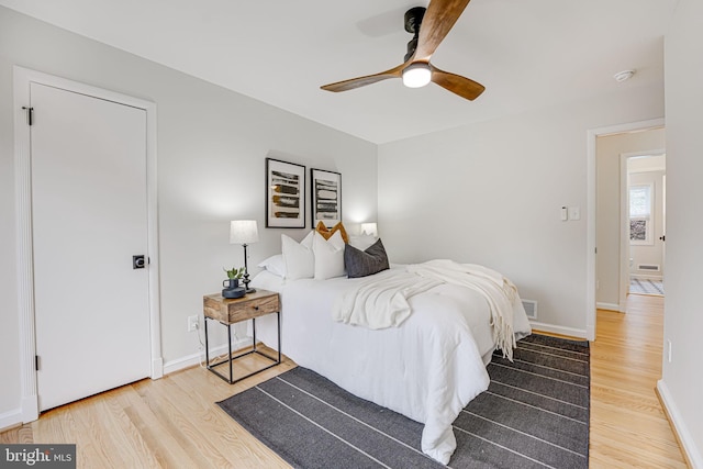 bedroom with ceiling fan, wood finished floors, visible vents, and baseboards