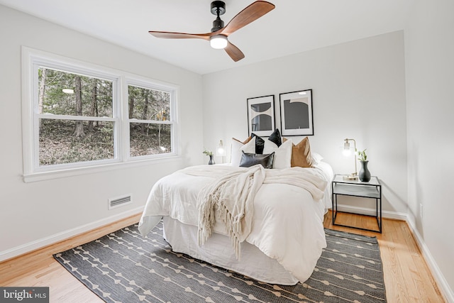 bedroom with visible vents, ceiling fan, baseboards, and wood finished floors