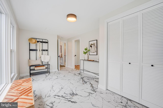 hallway featuring marble finish floor and baseboards