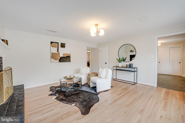 sitting room featuring light wood finished floors, baseboards, visible vents, and a notable chandelier